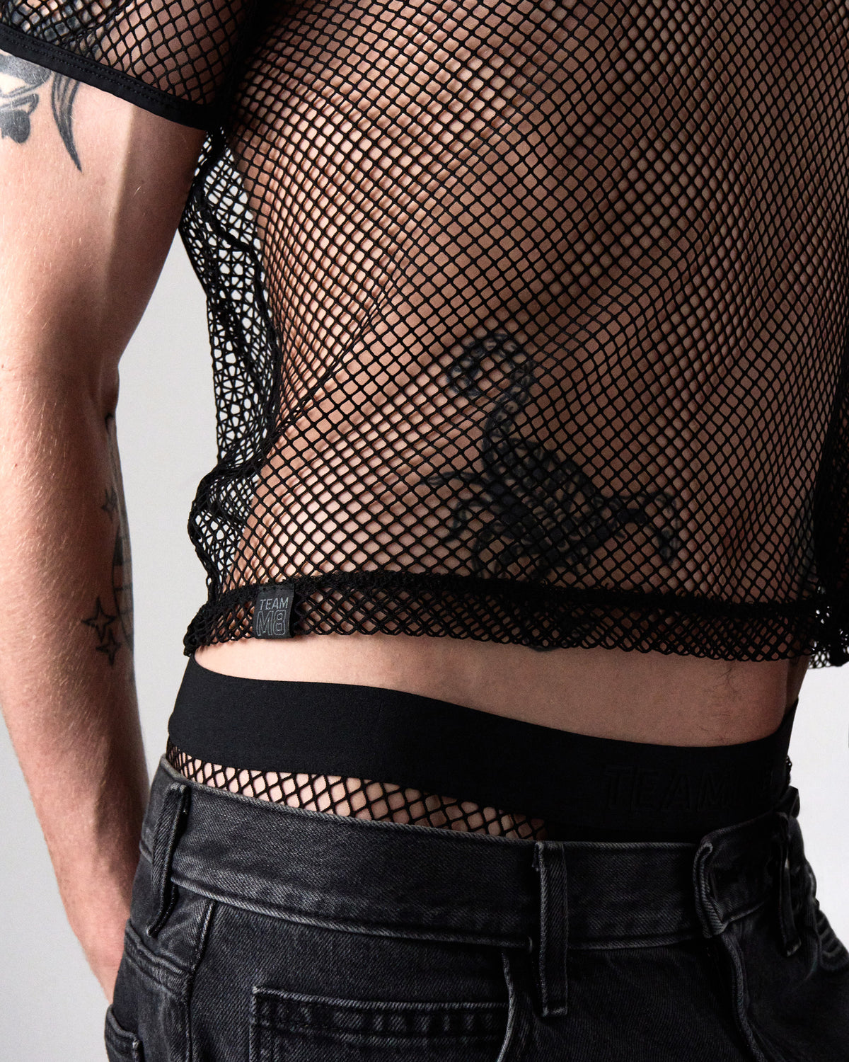 Edge Net Cropped Tee in Jet, close-up of the cropped hem and TEAMM8 label tab