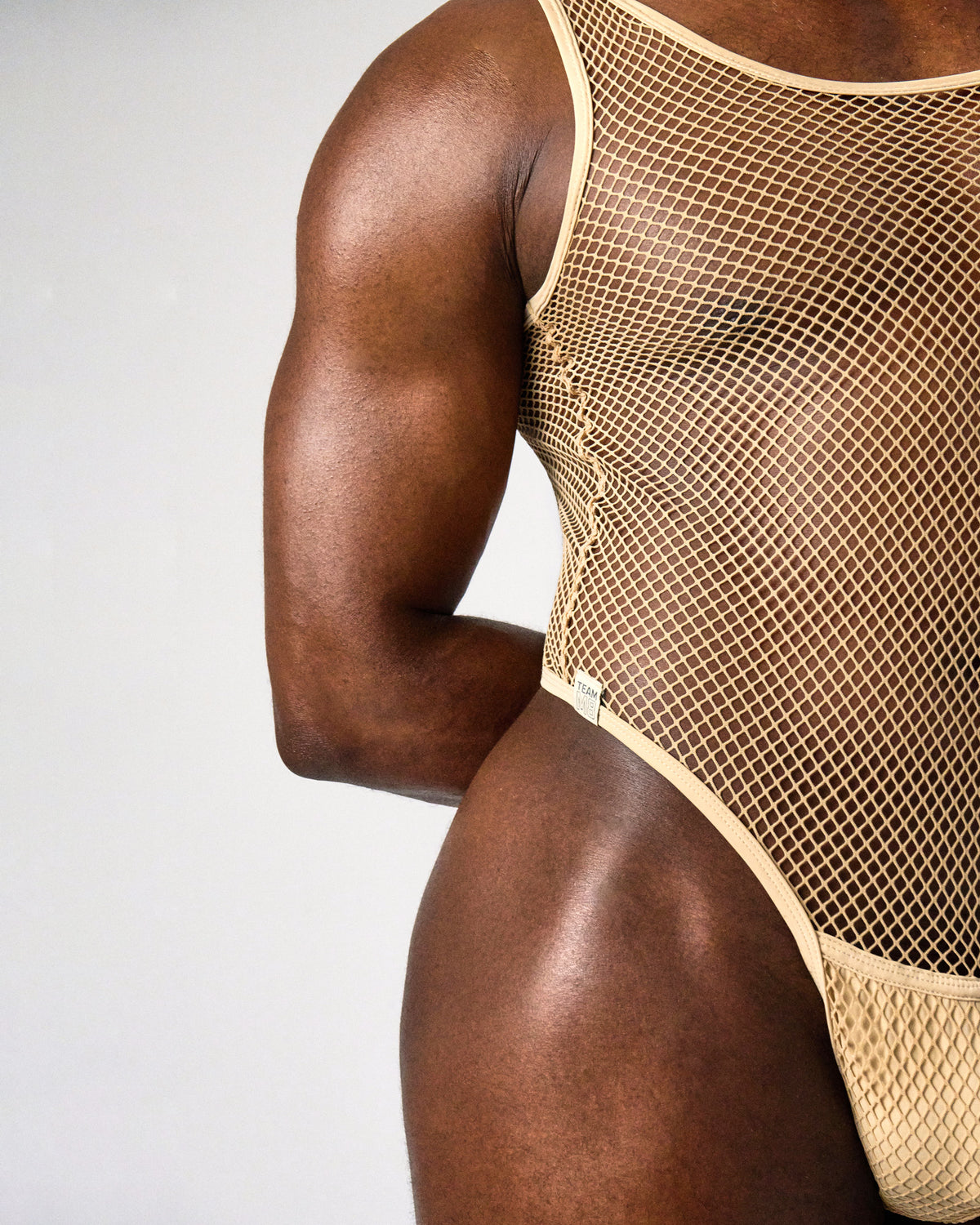 Edge Net Leotard in Sand, side close-up of the piped armhole, high-cut leg and label tab