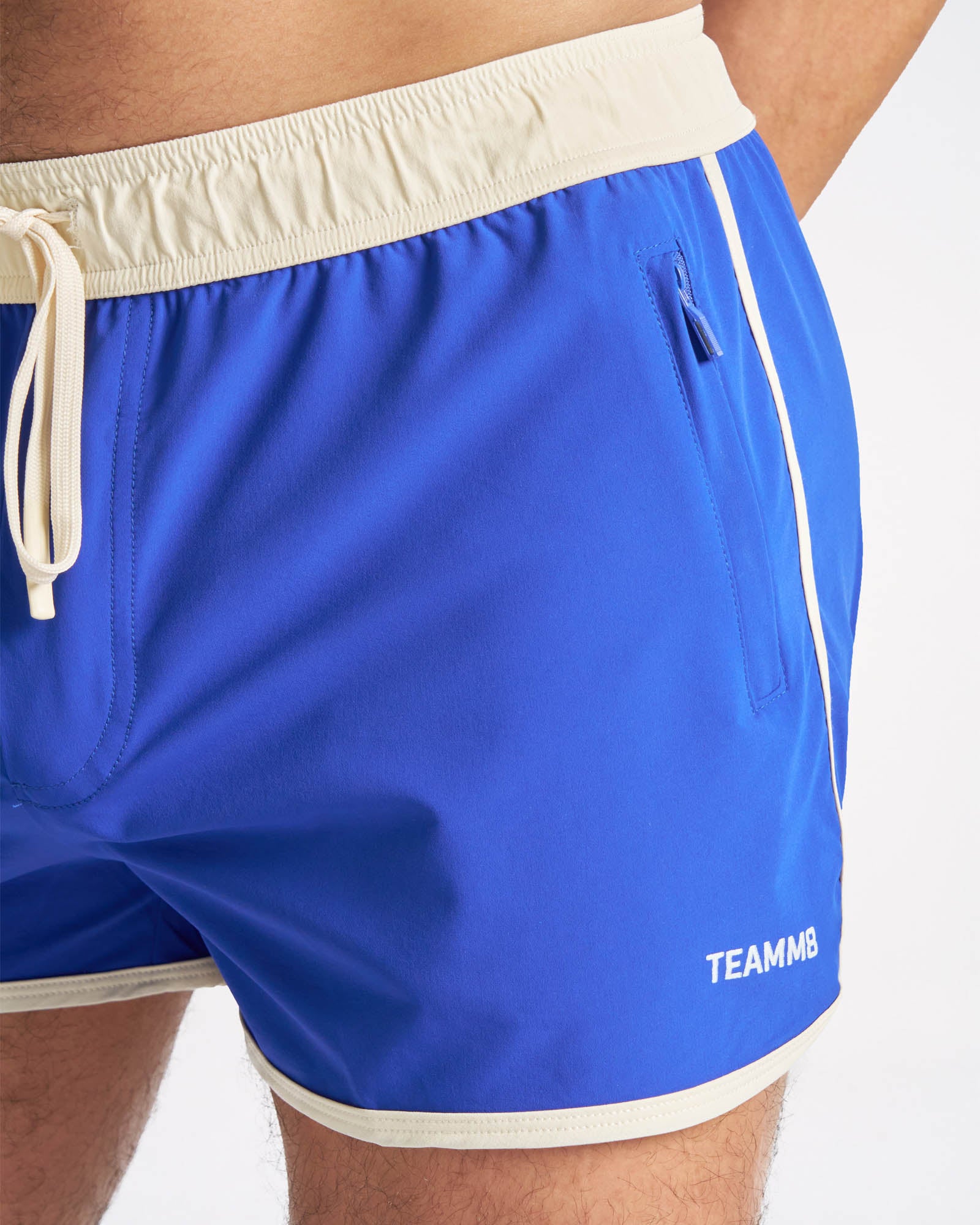 Blue shorts with a white waistband and 'TEAMM8' branding on a white background